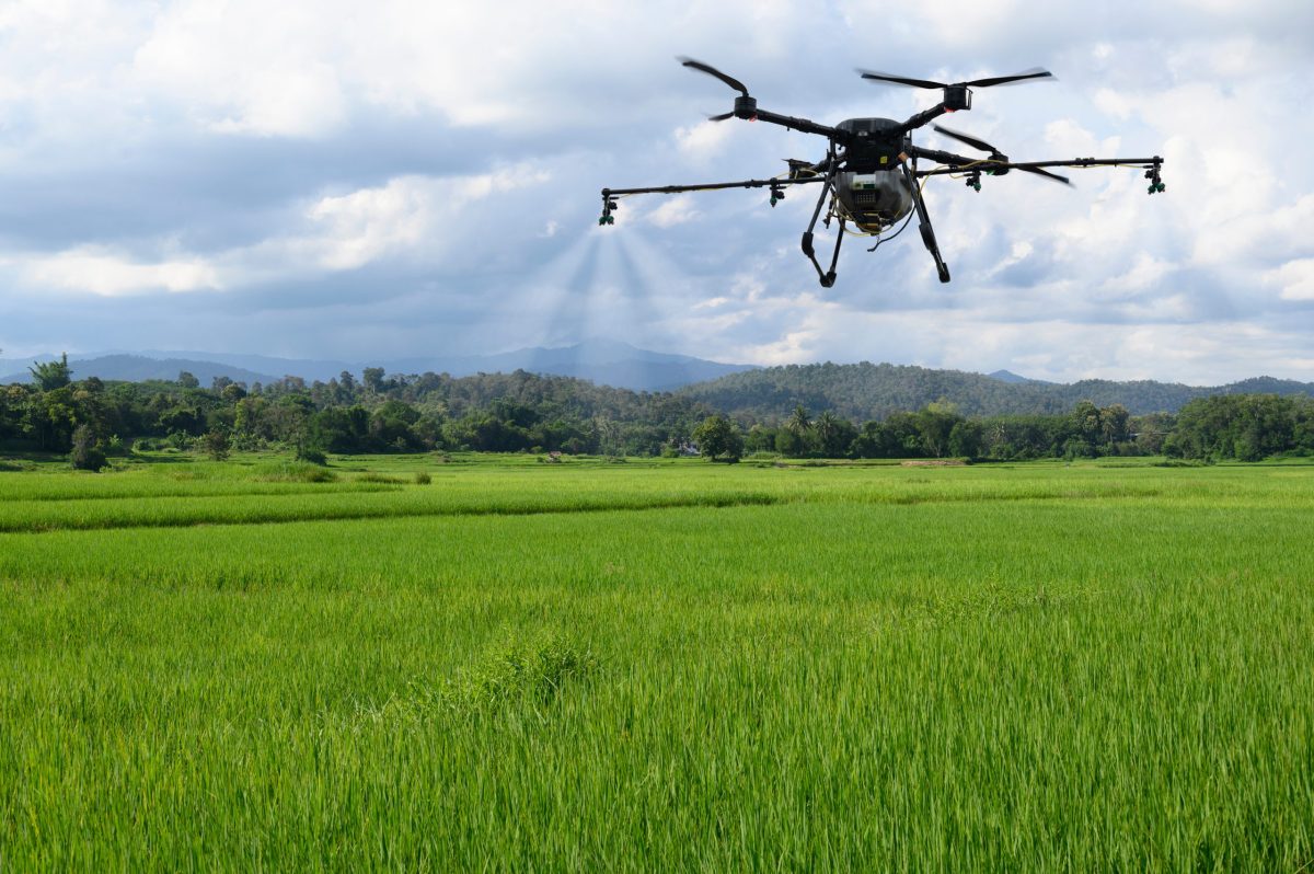 An agricultural drone is pictured hovering over a field.