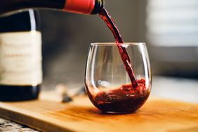 Red wine being poured into a stemless glass