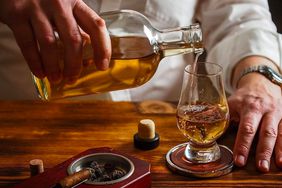 A person pours whiskey into a glass.