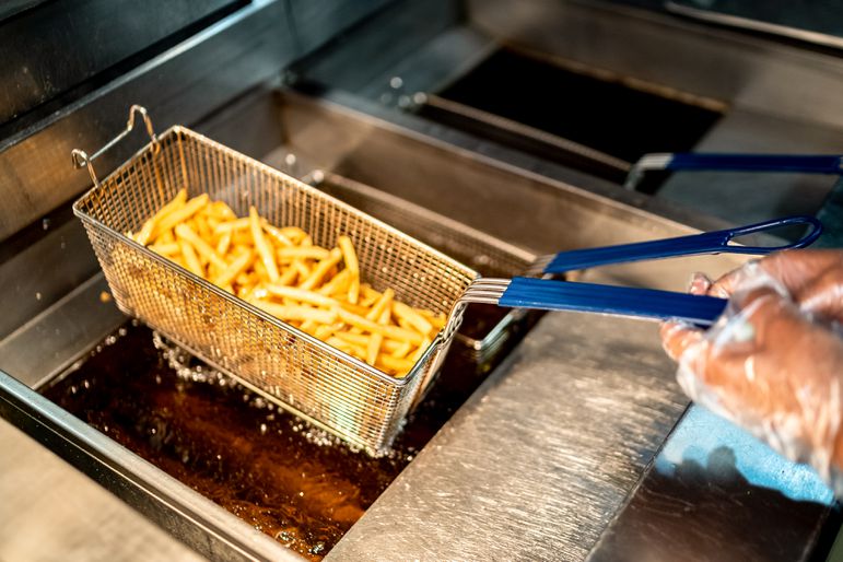 A fast food worker fries french fries