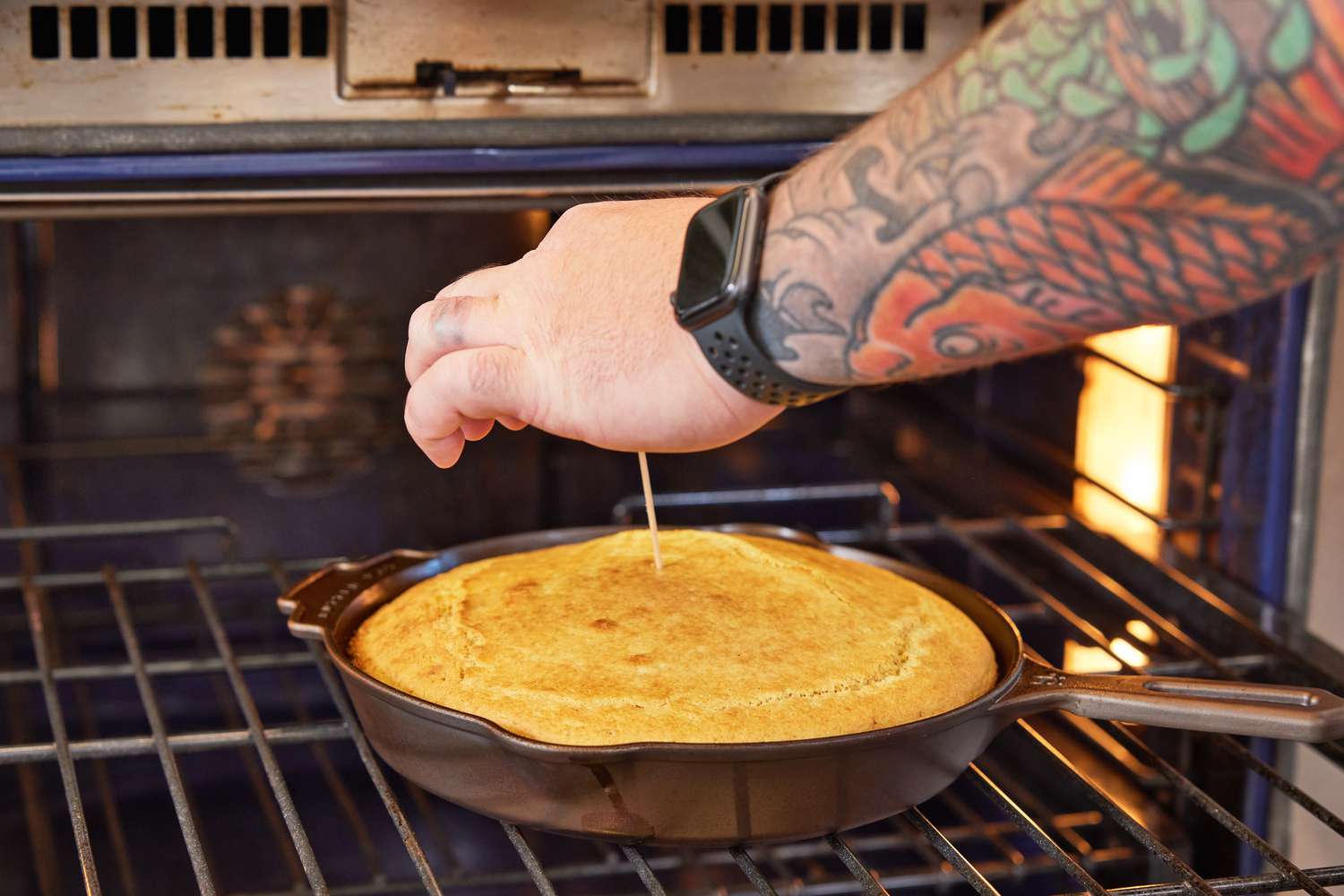 Close-up of person's hand pricking stick to cooked batter in Butter Pat Heather 10-Inch Skillet