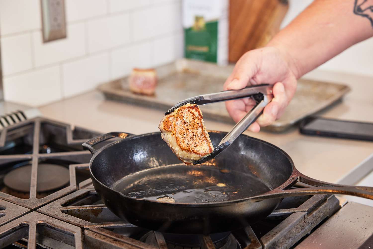 Person cooking meat in Lodge Blacklock Triple-Seasoned Cast Iron Pan - 10 1/4” Diameter