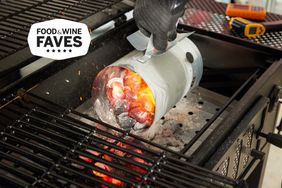 A person pouring hot coals in a Char-Griller Classic Cart Style Charcoal Grill