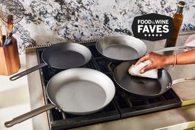 Four carbon steel pans on a stove being tested