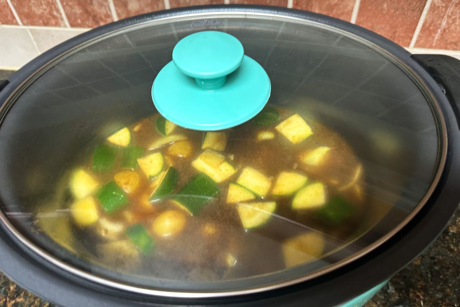 A closeup of food cooking in the GreenLife Cook Duo 6-Quart Nonstick Slow Cooker with the lid on