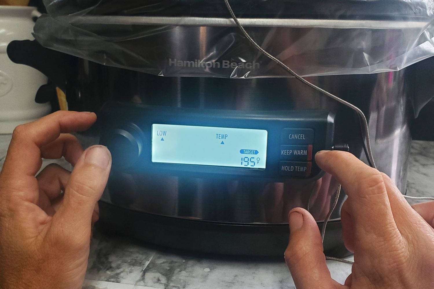 A person programming the Hamilton Beach Set & Forget Digital Programmable 6-Quart Slow Cooker