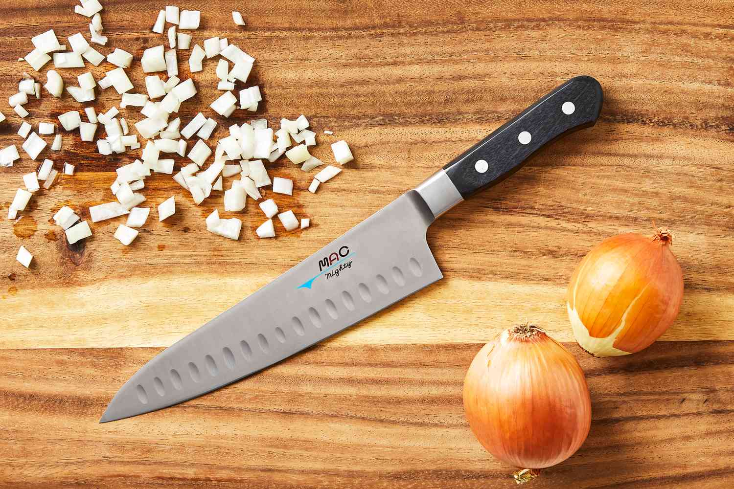 Mac Knife 8-Inch Hollow Edge Chef's Knife on a wooden cutting board with diced and whole onions