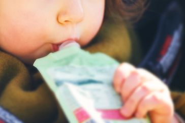 A child snacks on a fruit pouch