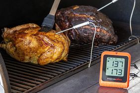 A ThermoPro meat thermometer being used to temp meat that is on a grill.