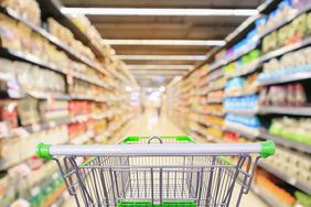 shopping cart in supermarket aisle with product shelves interior defocused blur background