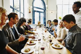 Laughing group of friends sitting at table in restaurant eating dessert