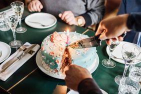 A person cuts a birthday cake at a restaurant