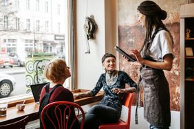 A server entertains two patrons at a cafe