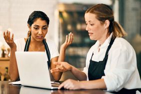 Two restaurants workers react to a review on a laptop