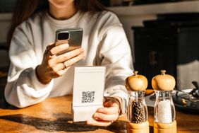 A person looks scans a QR code with their phone at a restaurant to pay