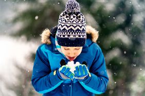 A young person plays with snow on a winter day