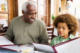 A man and child view menus at a restaurant table