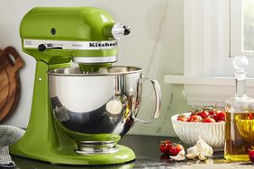 Williams Sonoma KitchenAid Artisan Stand Mixer on a kitchen counter next to a bowl of cherry tomatoes and olive oil.