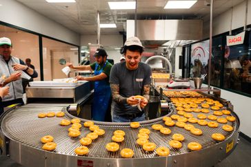 A worker prepares Krispy Kreme doughnuts during a press preview at the new Krispy Kreme location in central Paris on December 4, 2023