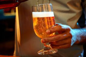 A beer bottle being poured into a glass