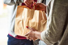 A delivery person hands off a food delivery bag