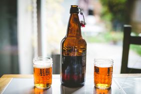 A Bottle Of Beer And Two Glasses Full Of Beer Sit On A Table