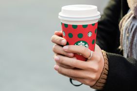 A person holds a hot Starbucks holiday cup