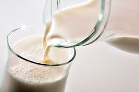 Heavy cream pouring from a pitcher into a glass