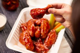 A person enjoys chicken wings ordered from GrubHub